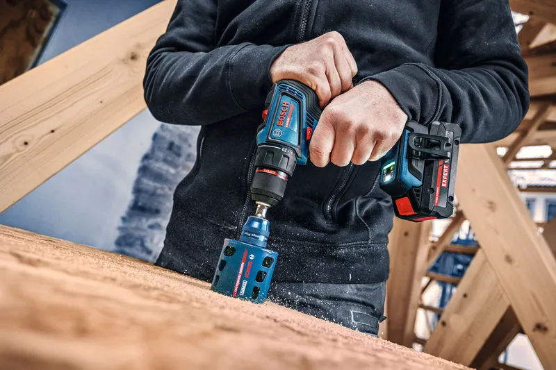 Iemand gebruikt een accuboormachine om een gat in een houten plank te maken.