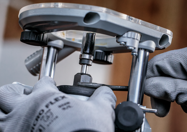 Een persoon die veiligheidsuitrusting draagt, stelt een elektrisch gereedschap af met een sleutel.