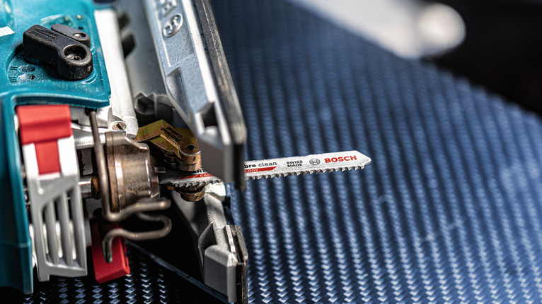 Decoupeerzaag met metalen zaagblad op een blauw oppervlak.