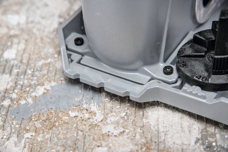 De basis van de muurfreesmachine rust op een stoffig betonnen oppervlak.