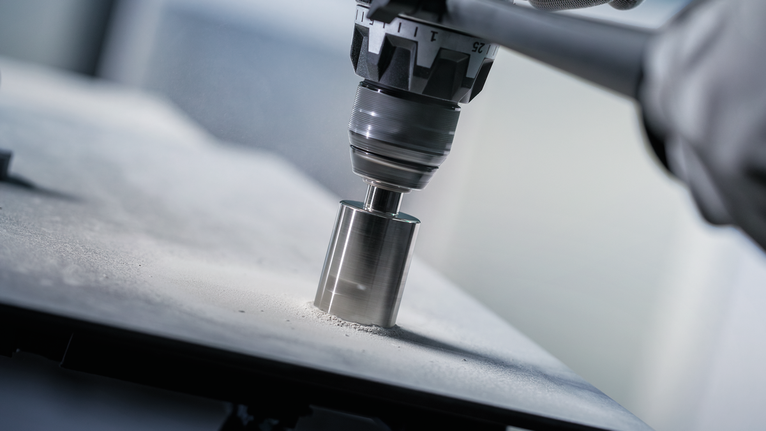 Een persoon die veiligheidsuitrusting draagt, boort een rond gat in een tegeloppervlak.