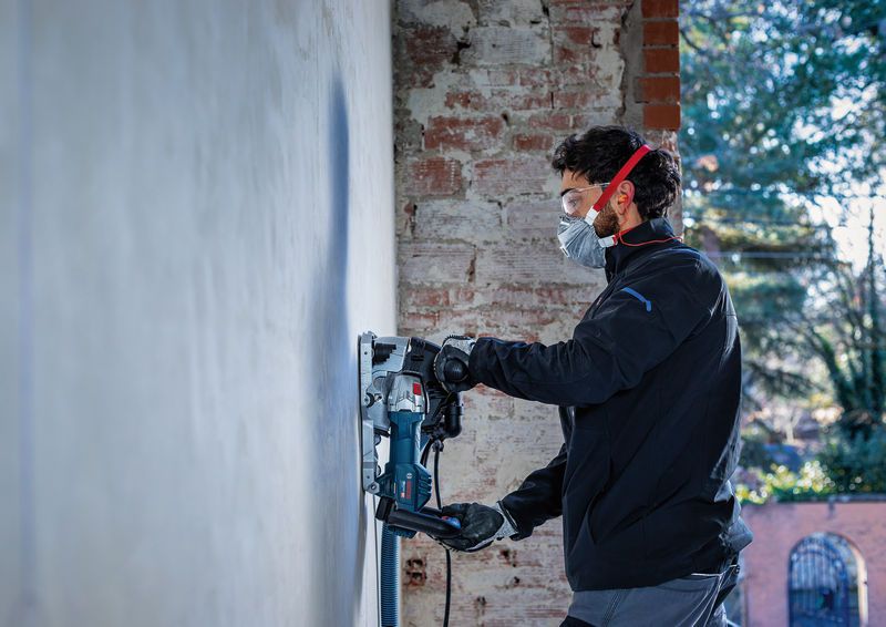 Een persoon die veiligheidsuitrusting draagt, bedient een muurfrees op een betonnen muur.