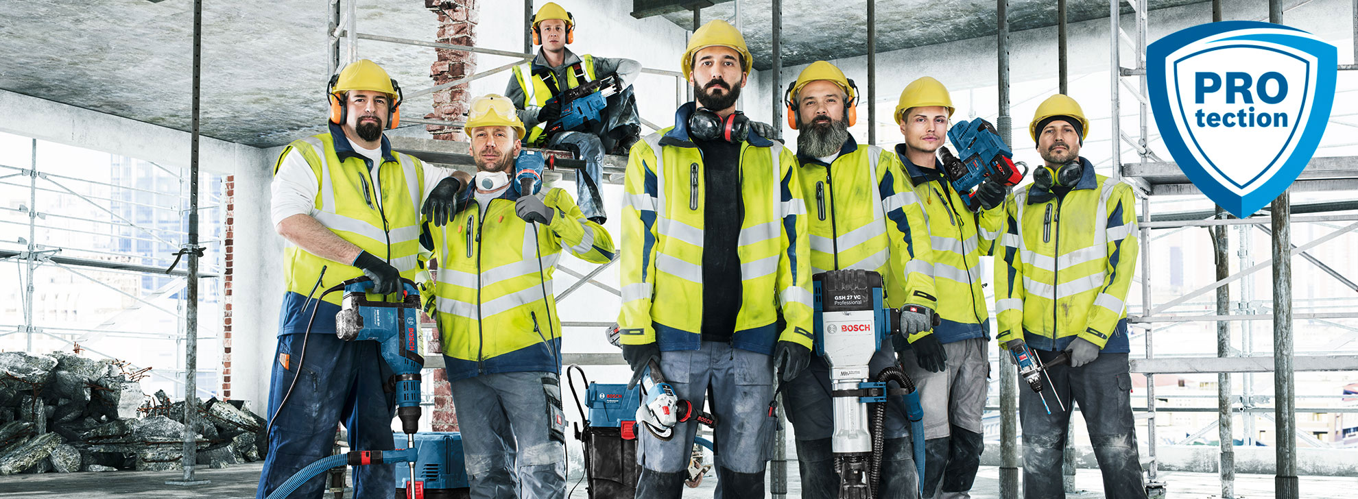 Syv menn i gule sikkerhetsjakker med Bosch verktøy på en byggeplass.