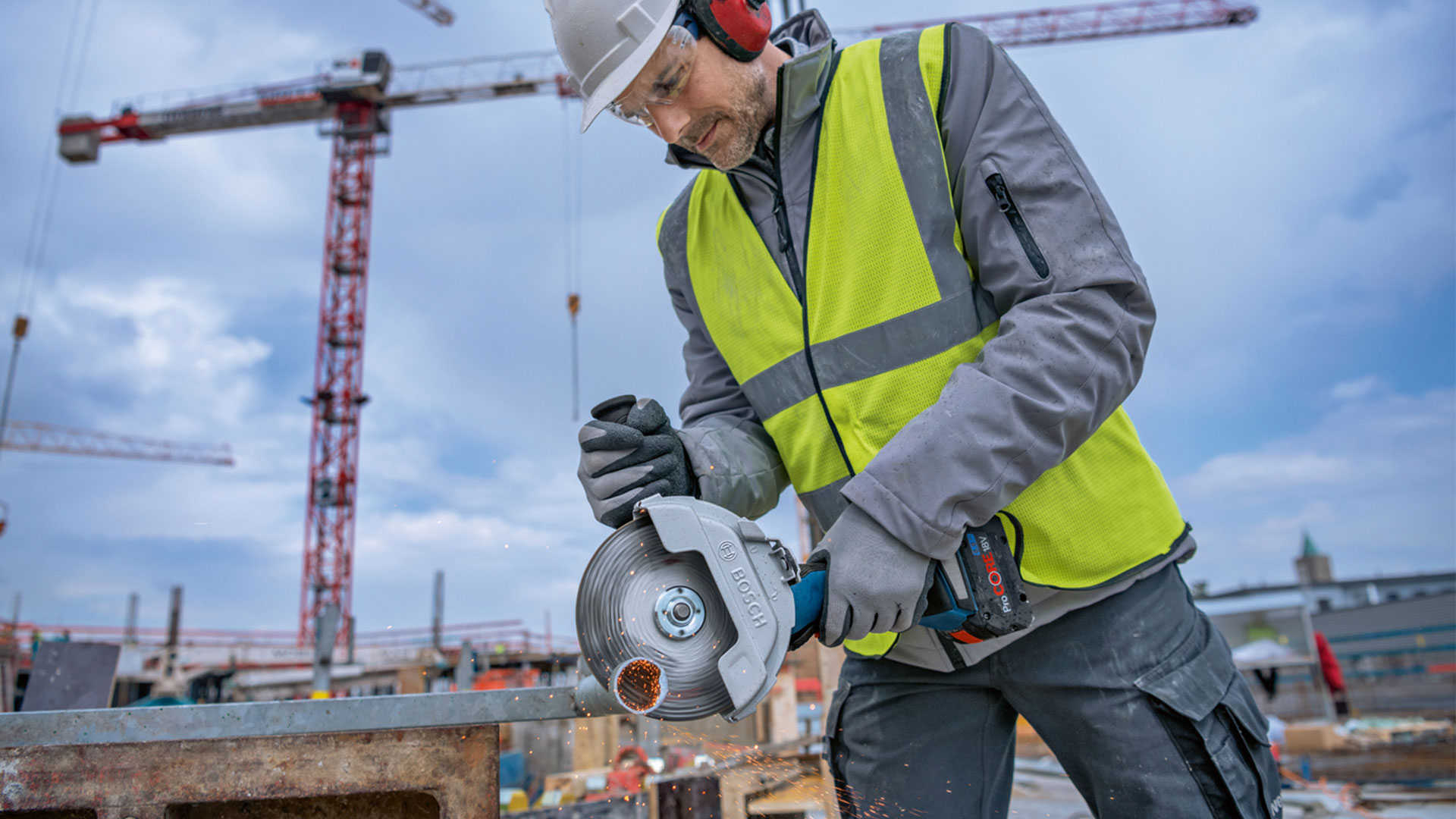En mann i verneutstyr bruker en Bosch sirkelsag på en byggeplass.