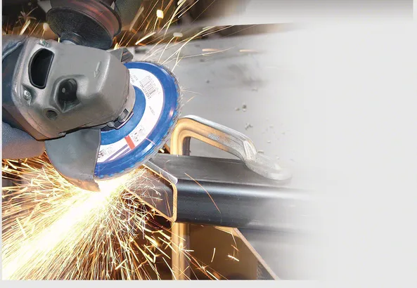 En person med sikkerhetsutstyr bruker en vinkelsliper og genererer gnister på en metallbjelke.