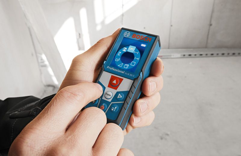Person som bruker en lasermåler for å beregne avstand inne i en bygning under bygging.