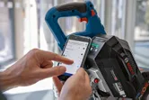En person justerer innstillingene for en batteridrevet gjærsag ved hjelp av en smarttelefonapp.