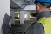 En person som bruker sikkerhetsutstyr bruker en lasermåler for å sjekke avstand i et byggeområde.