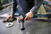 En person forbereder seg på å bruke en vinkelsliper på en metallbenk.