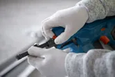 Person som bruker sikkerhetsutstyr justerer en batteridrevet betongspikerpistol.