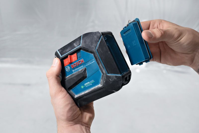 Person som holder et lasernivelleringsverktøy og fjerner batterirommet.