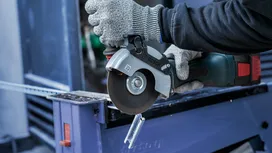 En person som bruker sikkerhetsutstyr bruker en sirkelsag til å skjære en metallkanal.