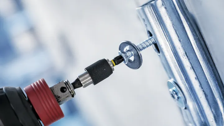 Batteridrevet drill som skrur en skrue inn i en metallbrakett.