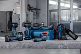 Batteridrevne poleringsmaskiner og tilbehør arrangert på en arbeidsbenk i et industriverksted.