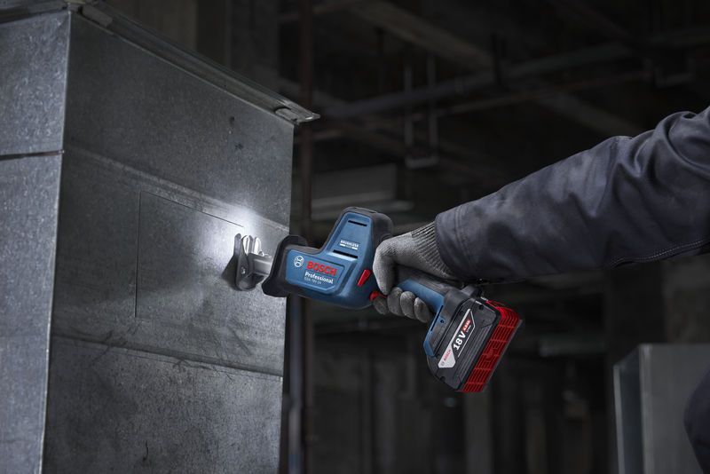 En person med sikkerhetsutstyr kutter metallplater med en batteridrevet bajonettsag.