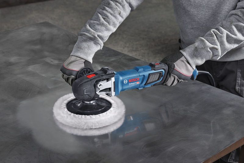 En person med sikkerhetsutstyr polerer en metallplate med en elektrisk poleringsmaskin.