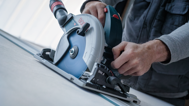 Person som bruker en sirkelsag for å skjære en rett linje i et platemateriale.