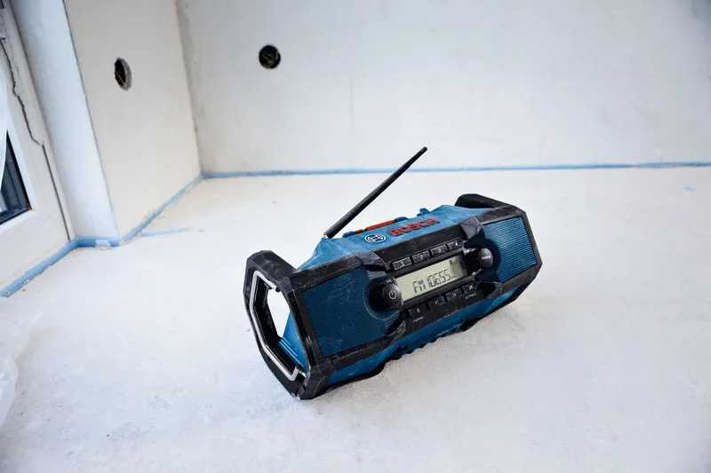 En robust blå radio står på gulvet i et delvis ferdig rom.