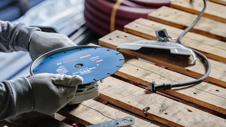 En person med sikkerhetsutstyr justerer et elektroverktøy på en trepall.