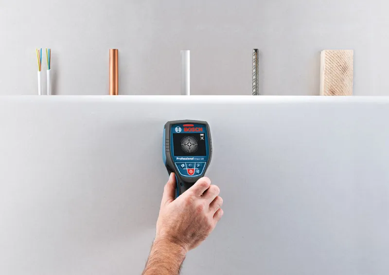 D-tect 120 A person uses a wallscanner detector to check behind a drywall surface.