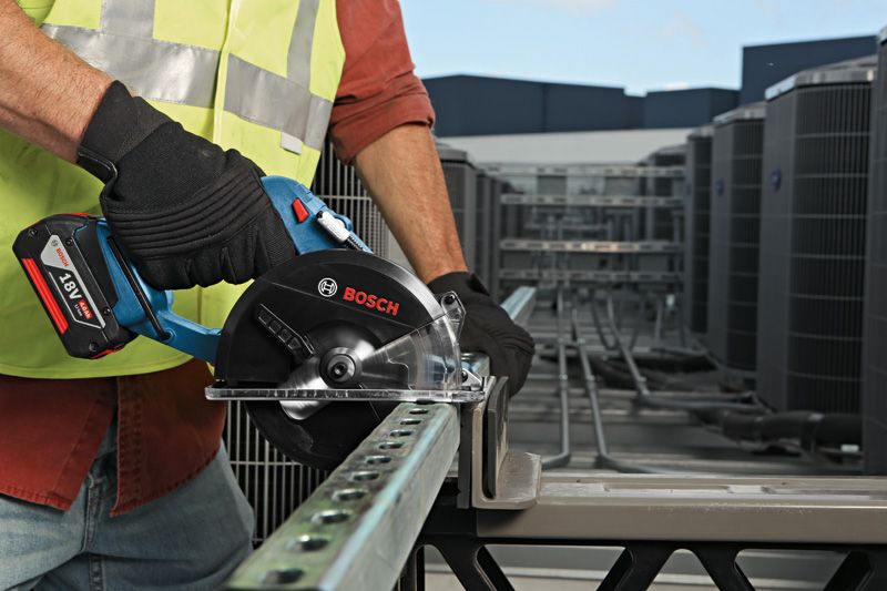 Person wearing safety equipment uses a cordless circular saw to cut a metal channel.