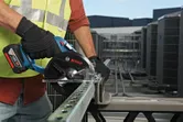 Person wearing safety equipment uses a cordless circular saw to cut a metal channel.