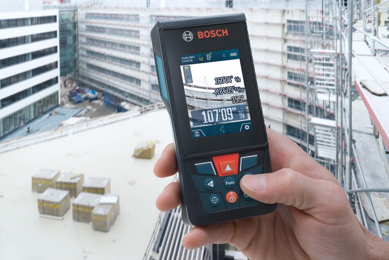 Person using a laser measure on a building construction site.