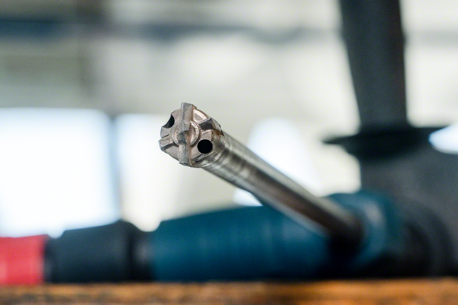 Close-up of a rotary hammer drill bit attached to a power tool.