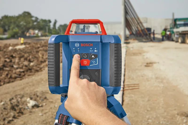 Person operating a laser leveling tool at a construction site.