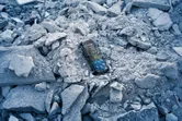 Laser measure device lying on a pile of broken concrete rubble.