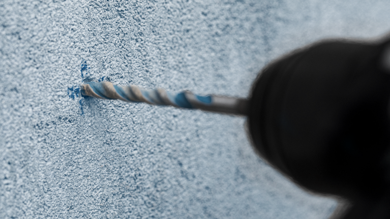 EXPERT MultiConstruction CYL-9 Drill Bit Set 4/5/6/8 mm 4-pc Drill creating a hole in a textured concrete wall.