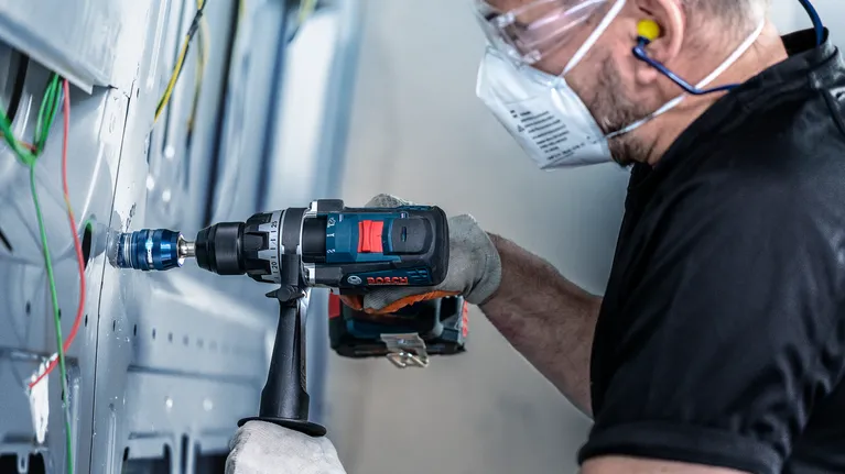 EXPERT Sheet Metal Hole Saw 20 x 5 mm A person wearing safety equipment drills a hole into a metal panel.