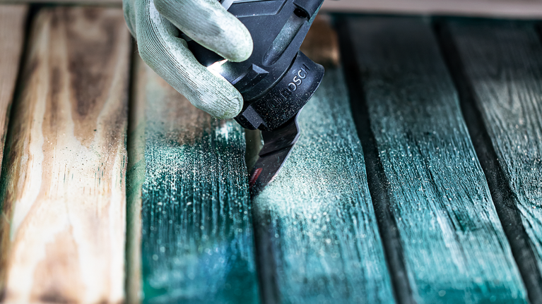 EXPERT Sanding Finger Coarse AVZ 32 RT4 Multitool Sanding Plate 32 x 53 mm Person wearing safety equipment sands paint from wood planks with a power tool.