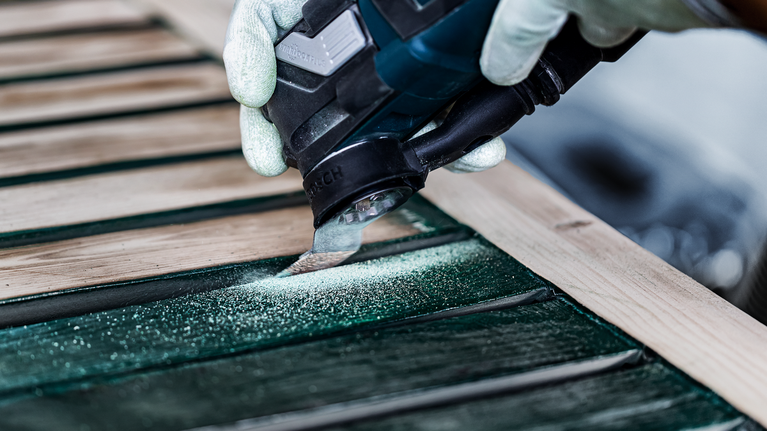 EXPERT Sanding Finger Coarse AVZ 32 RT4 Multitool Sanding Plate 32 x 53 mm Person wearing safety equipment sanding wood slats with a power tool.