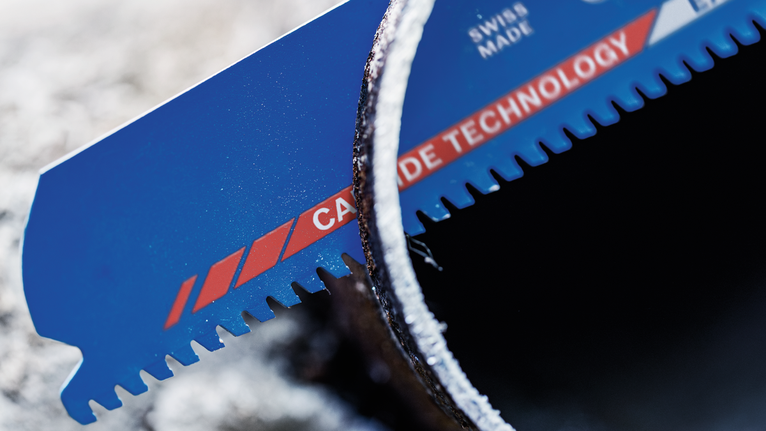 EXPERT ‘Thick Tough Metal’ S 955 CHC Reciprocating Saw Blade 1-pc Person wearing safety equipment uses a power tool to cut an old metal pipe outdoors.