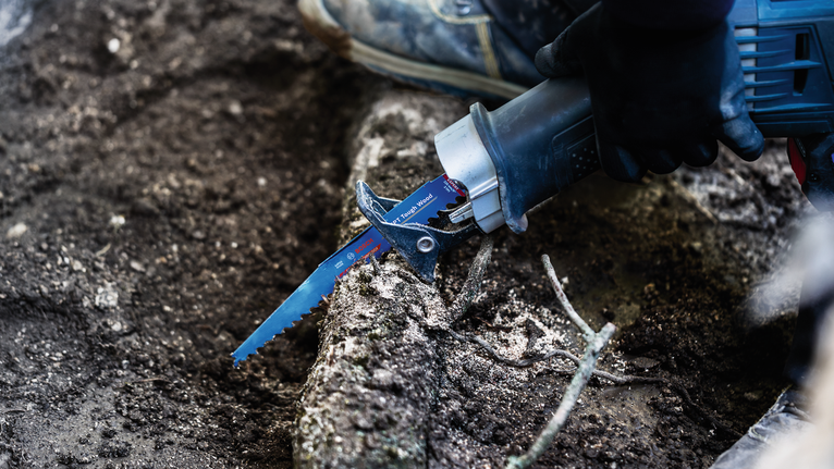EXPERT ‘Tough Wood’ S 1142 KHM Reciprocating Saw Blade 1-pc A worker wearing safety equipment uses a reciprocating saw to cut through tree roots.