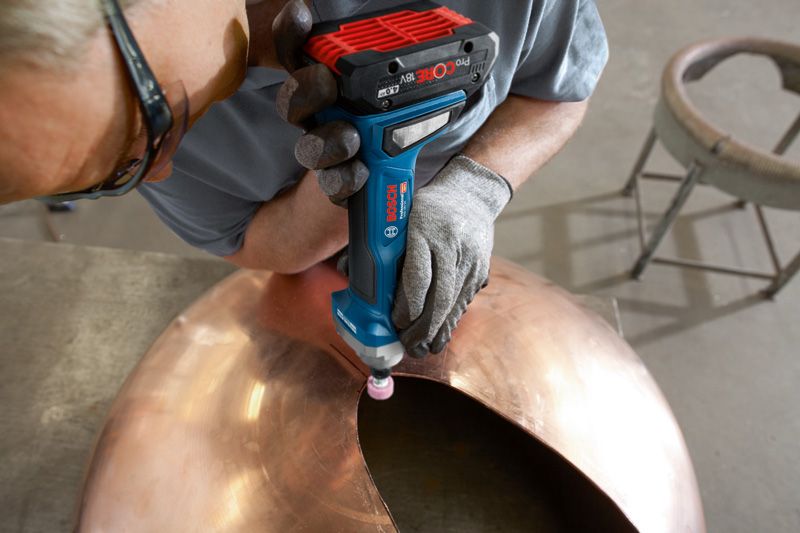 GGS 18V-20 A person wearing safety equipment grinds the edge of a large metal dome.