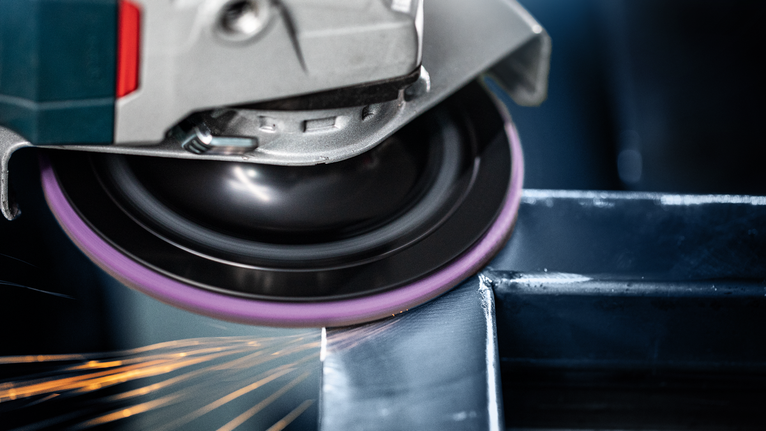 EXPERT N477 SCM Disc for Angle Grinders 125 x 22 mm, Extra Coarse Angle grinder smoothing a steel beam, producing sparks.