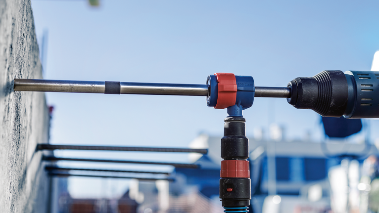 EXPERT SDS Clean max-8X Hammer Drill Bit Set 20 x 400 x 650 Rotary hammer drilling a hole into a concrete wall outdoors.