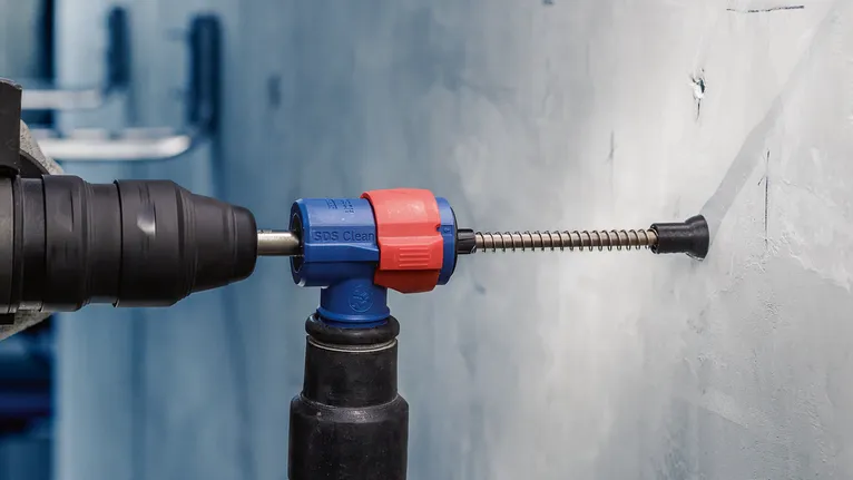 EXPERT SDS Clean max Connector for Hammer Drill Bit Rotary hammer with a dust extraction device drills into a concrete wall.