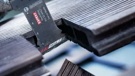 Oscillating multi-tool blade cutting through grooved composite decking.
