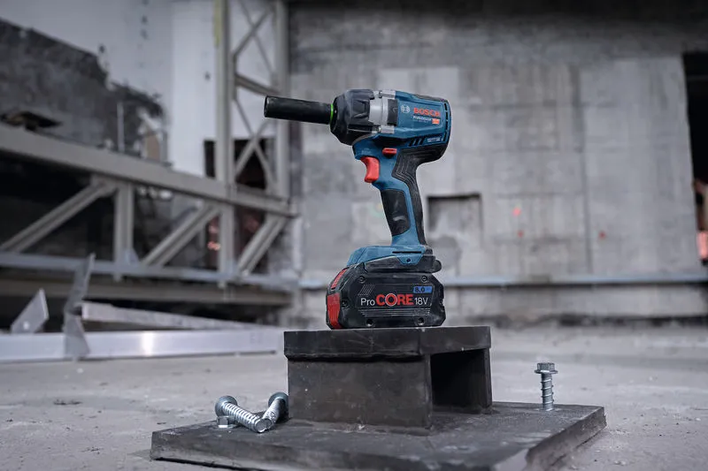 GDS 18V-750 C Cordless impact wrench resting on a metal block with two large bolts nearby.