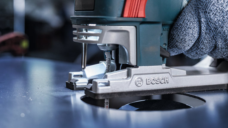 PRO Metal curve T118EOF Jigsaw Blade, 83 mm, 5 pcs Person wearing safety equipment guides a jigsaw to cut a circular hole in metal.