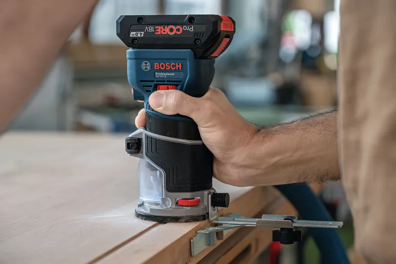 GKF 18V-8 A person uses a cordless palm router to trim the edge of a wooden board.