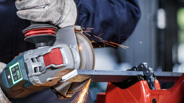 PRO Metal Bonded Cutting Disc, 125 x 2.5 x 22.23 mm, X-Lock, With Depressed Centre A person wearing safety equipment grinds metal with an angle grinder, creating sparks.