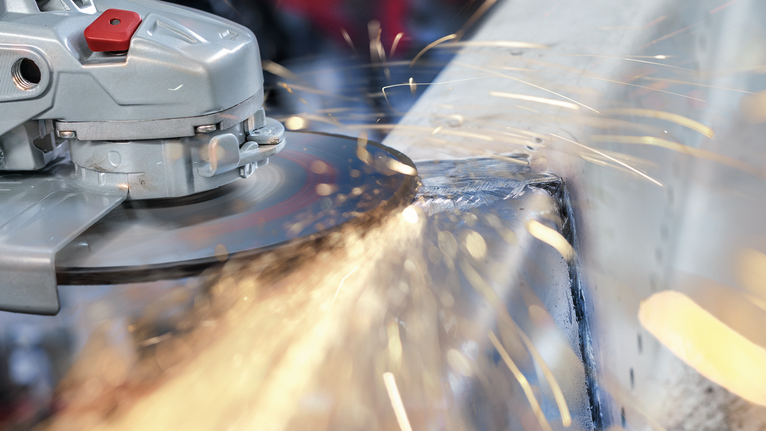 PRO Metal Bonded Grinding Disc, 180 x 6 x 22.23 mm Angle grinder cutting through metal, producing bright sparks.