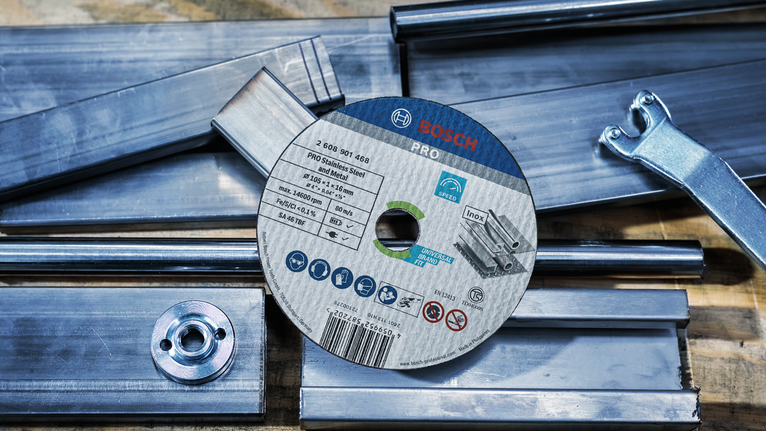PRO Stainless Steel and Metal Cutting Disc, 105 x 1 x 16 mm Cutting disc placed on metal bars and a wrench on a wooden workbench.