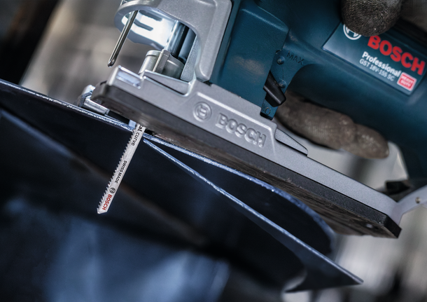 PRO Metal curve T118EOF Jigsaw Blade, 83 mm, 5 pcs A person wearing safety equipment uses a jigsaw to cut a sheet of metal.