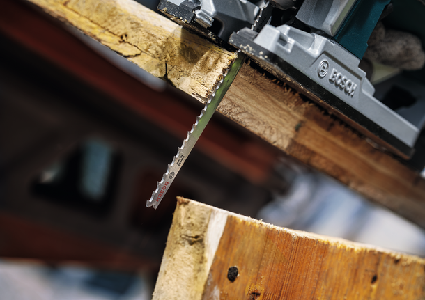 PRO Multi Material thick and thin T345XF Jigsaw Blade, 132 mm, 3 pcs Jigsaw blade cutting through a thick wooden plank in a workshop.