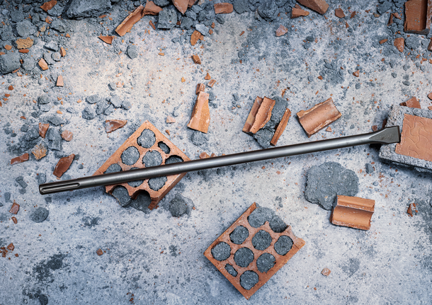 PRO SDS max-4C Flat Chisel, 25 x 300 mm Chisel bit lying on broken bricks and concrete debris.